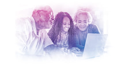 Grandparents looking at laptop with granddaughter in kitchen