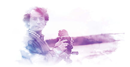 man with camera on tripod at lake